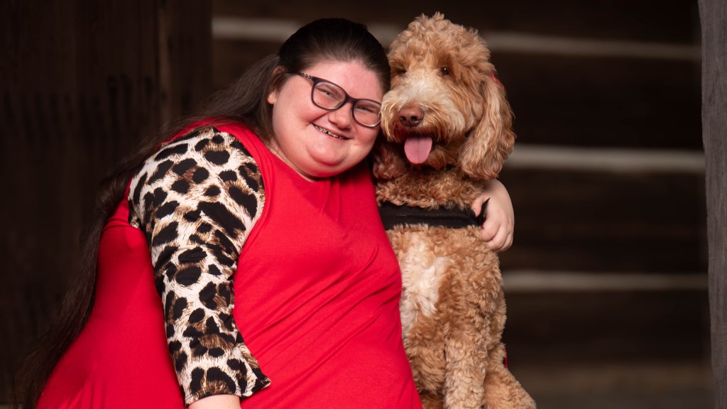 Kylie sitting with her arm around Bella. Kylie is wearing a read dress with leopard print sleeves. 
